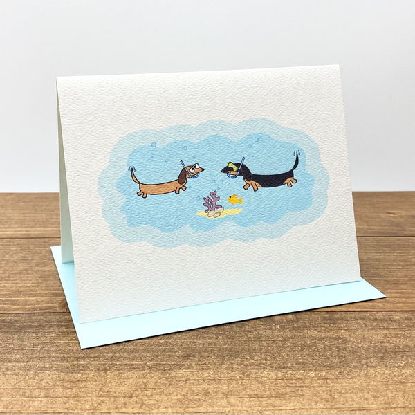 Note card featuring two dachshunds under the sea wearing snorkeling gear.