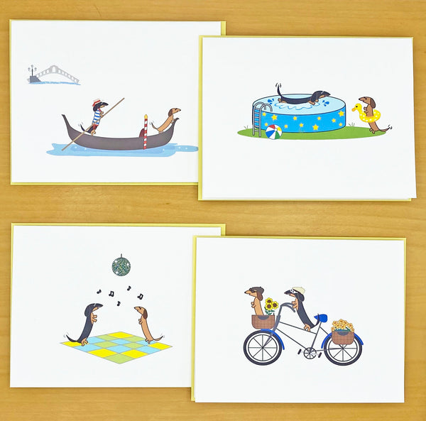 Assorted dachshund note cards, two dachshunds on gondola one dressed as a gondolier , two dachshunds at pool with one splashing in pool and the other in bright yellow duck floatie, two dachshunds dancing on colorful dance floor under a disco ball, two dachshunds wearing goggles and caps riding a bicycle with baskets full of flowers and one dachshund riding in the basket