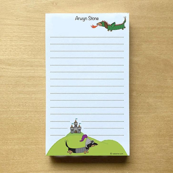 One dachshund dressed as dragon and the other as a knight with medieval castle in background in this  personalized and lined notepad