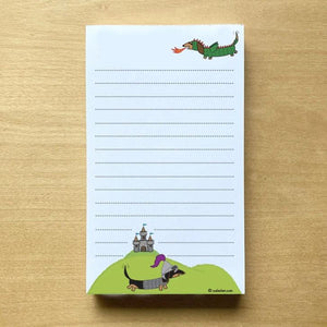 One dachshund dressed as dragon and the other as a knight with medieval castle in background in this lined notepad